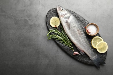 Photo of Fresh raw seabass fish with spices on grey table, top view and space for text. Seafood delicacies