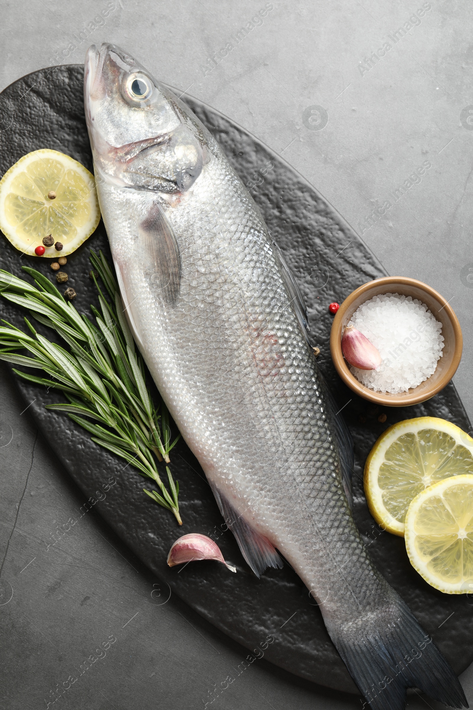 Fresh raw seabass with spices on grey table, top view. Fish and seafood delicacies Photo of Fresh raw seabass with spices on grey table, top view. Fish and seafood delicacies
