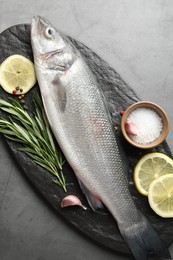Photo of Fresh raw seabass with spices on grey table, top view. Fish and seafood delicacies