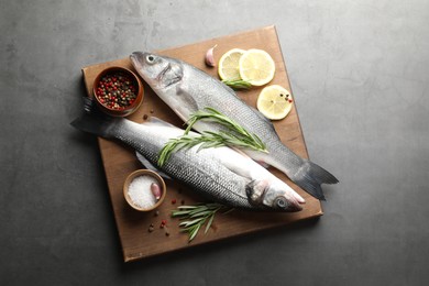 Photo of Fresh raw seabass with spices on grey table, top view. Fish and seafood delicacies