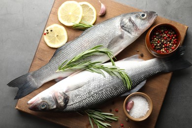 Photo of Fresh raw seabass with spices on grey table, top view. Fish and seafood delicacies