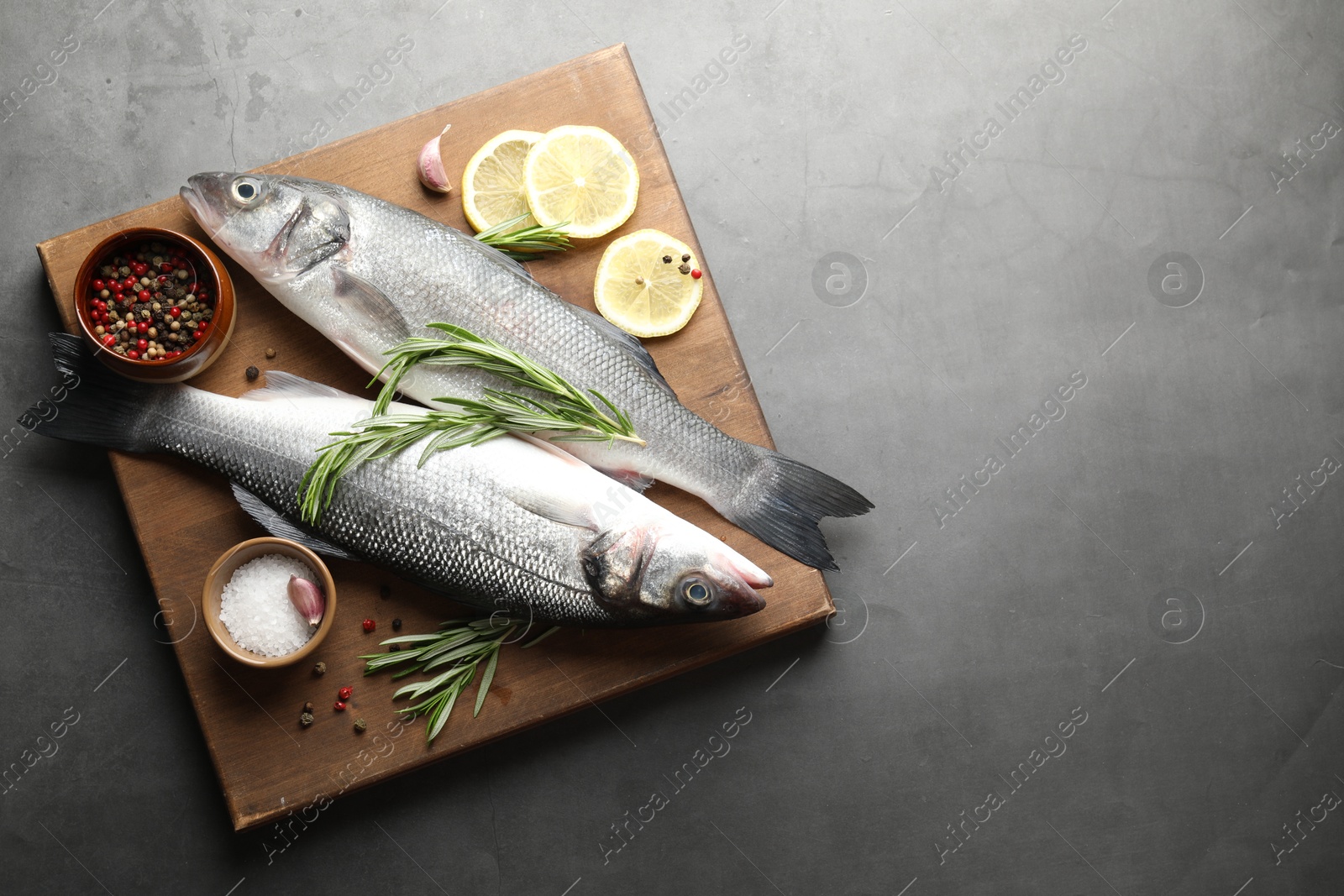 Fresh raw seabass fish with spices on grey table, top view and space for text. Seafood delicacies Photo of Fresh raw seabass fish with spices on grey table, top view and space for text. Seafood delicacies