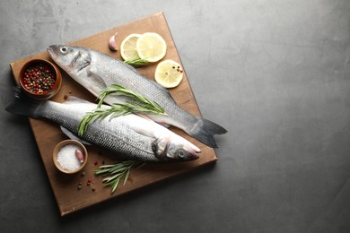 Photo of Fresh raw seabass fish with spices on grey table, top view and space for text. Seafood delicacies