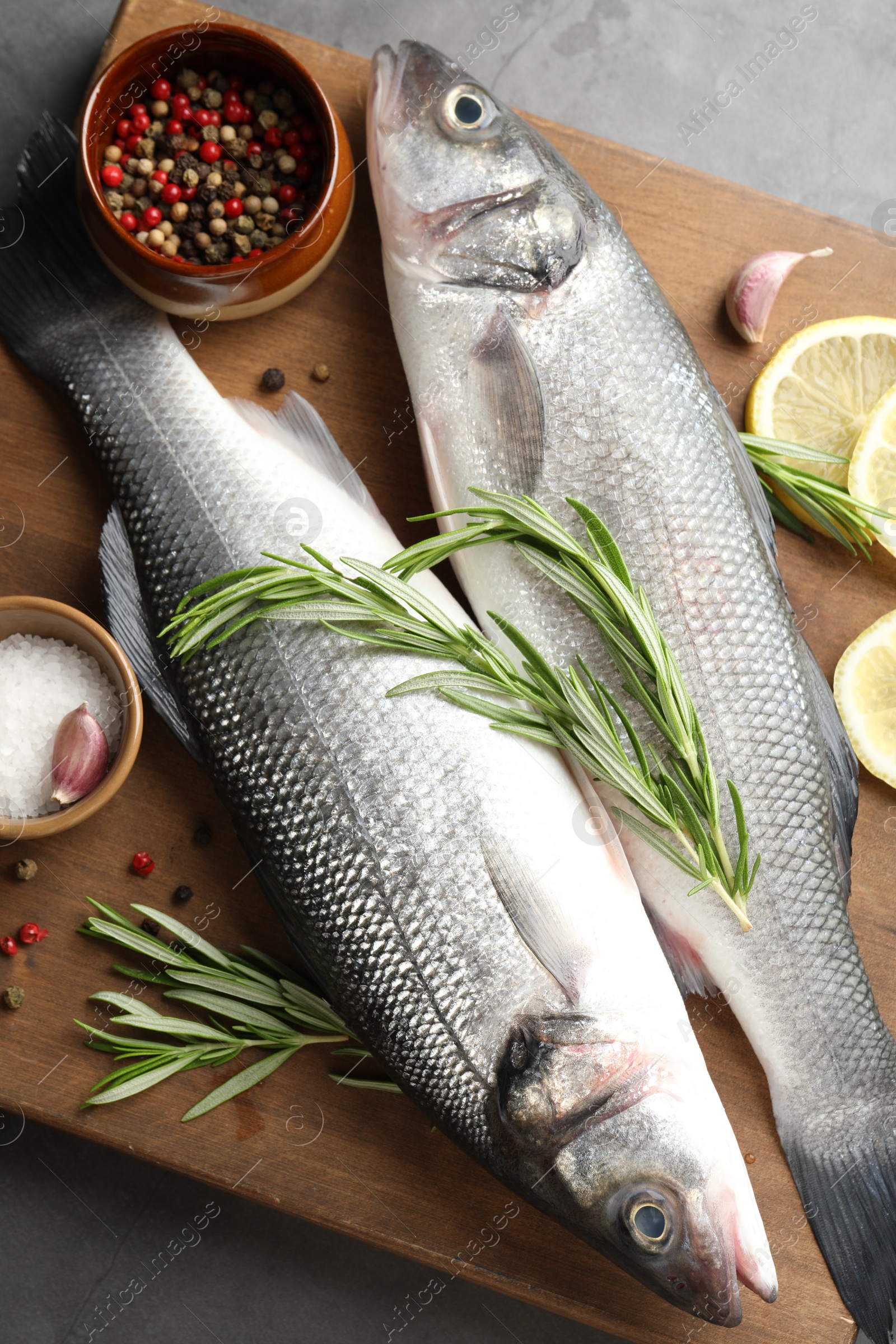 Fresh raw seabass with spices on grey table, top view. Fish and seafood delicacies Photo of Fresh raw seabass with spices on grey table, top view. Fish and seafood delicacies