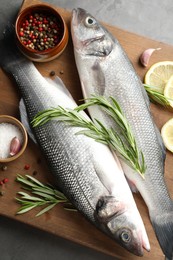 Photo of Fresh raw seabass with spices on grey table, top view. Fish and seafood delicacies