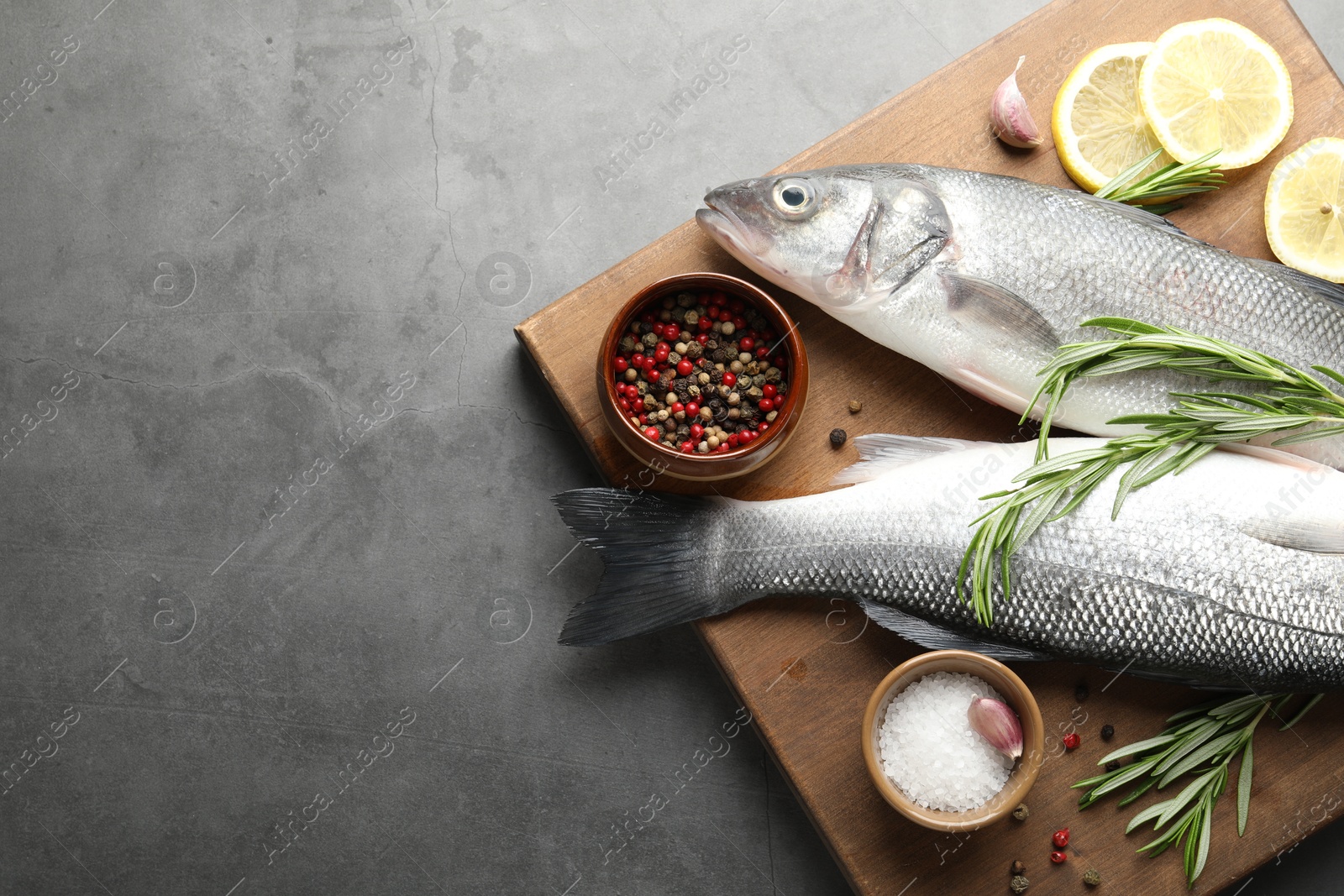 Fresh raw seabass fish with spices on grey table, top view and space for text. Seafood delicacies Photo of Fresh raw seabass fish with spices on grey table, top view and space for text. Seafood delicacies