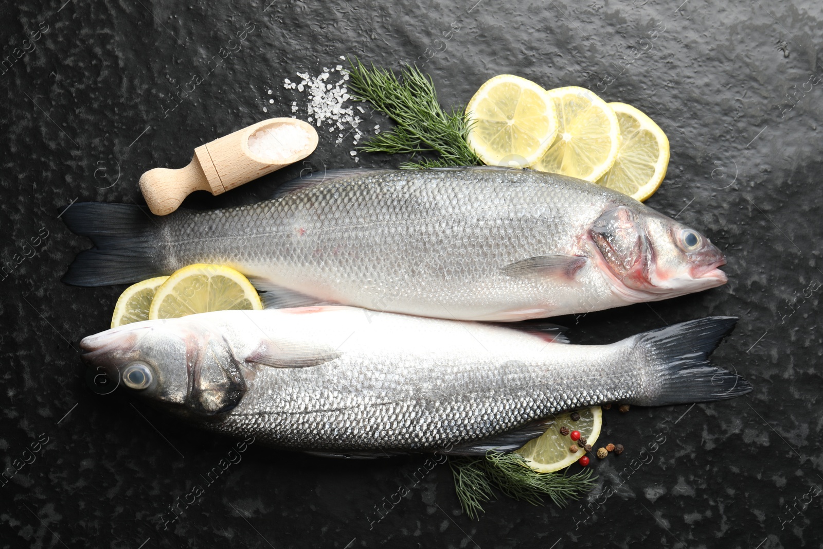 Fresh raw seabass with spices on black table, flat lay. Fish and seafood delicacies Photo of Fresh raw seabass with spices on black table, flat lay. Fish and seafood delicacies