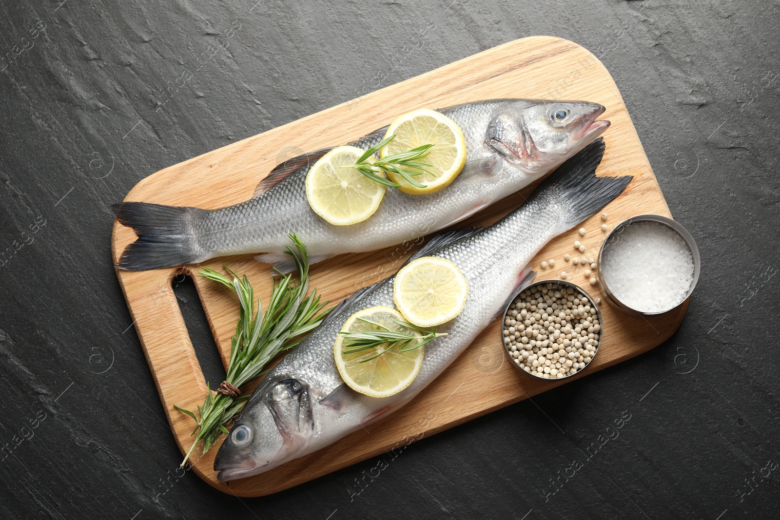 Fresh raw seabass with spices on black table, top view. Fish and seafood delicacies Photo of Fresh raw seabass with spices on black table, top view. Fish and seafood delicacies