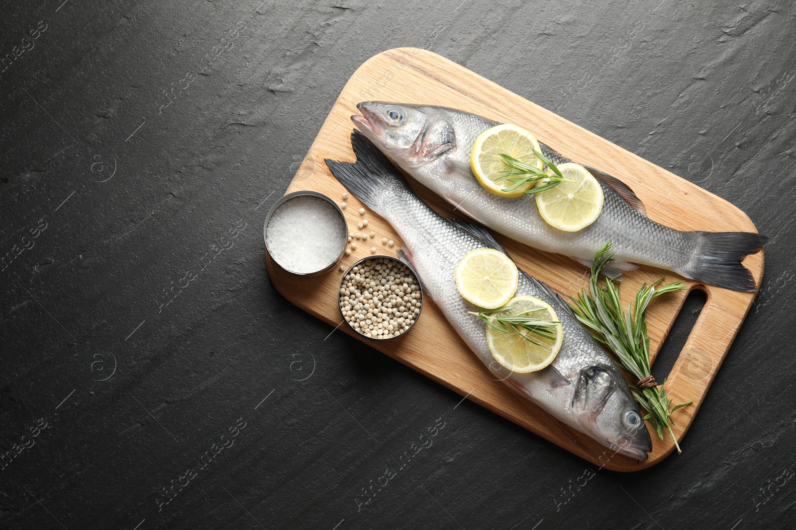 Fresh raw seabass fish with spices on black table, top view and space for text. Seafood delicacies Photo of Fresh raw seabass fish with spices on black table, top view and space for text. Seafood delicacies