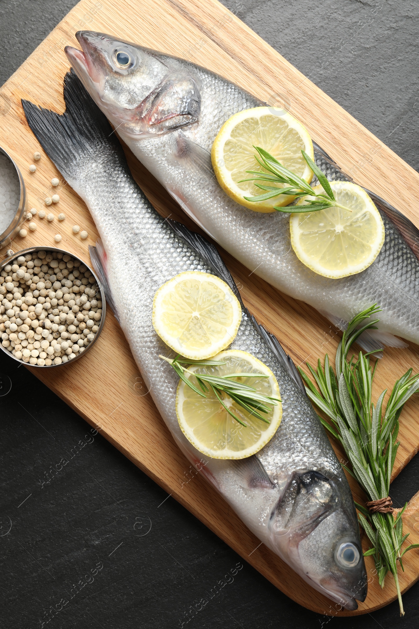 Fresh raw seabass with spices on black table, top view. Fish and seafood delicacies Photo of Fresh raw seabass with spices on black table, top view. Fish and seafood delicacies
