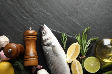 Photo of Fresh raw seabass fish with spices on black table, flat lay and space for text. Seafood delicacies