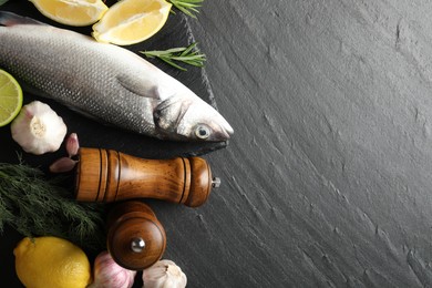 Photo of Fresh raw seabass fish with spices on black table, flat lay and space for text. Seafood delicacies