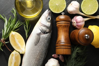 Photo of Fresh raw seabass with spices on black table, flat lay. Fish and seafood delicacies