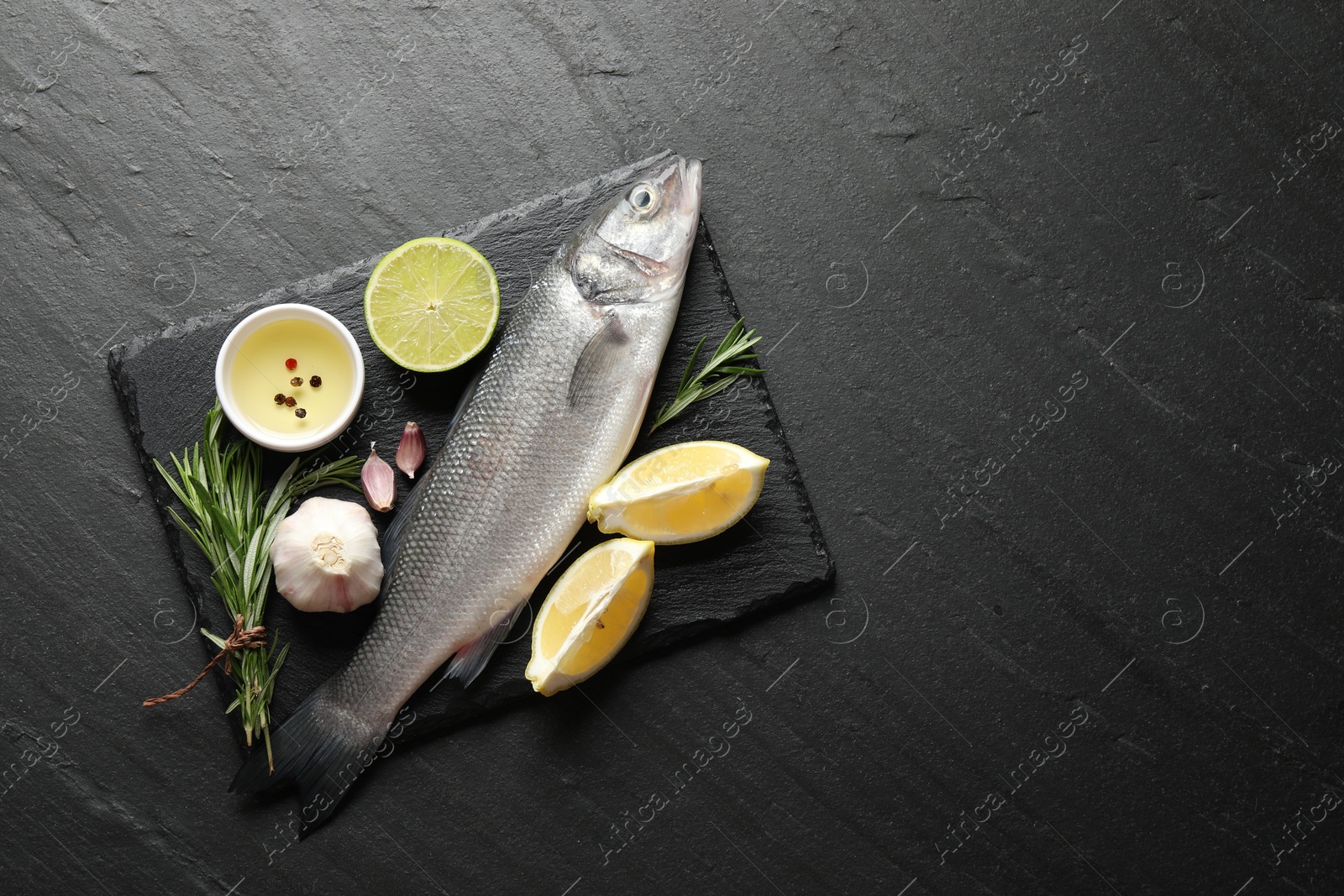 Fresh raw seabass fish with spices on black table, top view and space for text. Seafood delicacies Photo of Fresh raw seabass fish with spices on black table, top view and space for text. Seafood delicacies