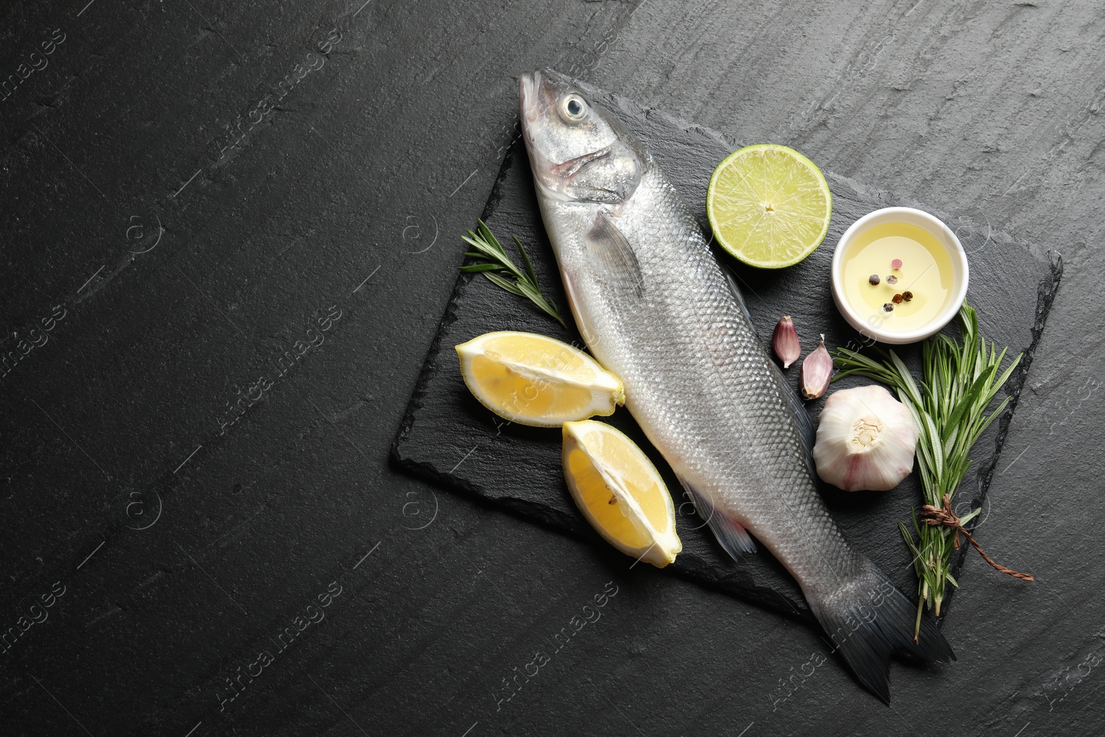 Fresh raw seabass fish with spices on black table, top view and space for text. Seafood delicacies Photo of Fresh raw seabass fish with spices on black table, top view and space for text. Seafood delicacies