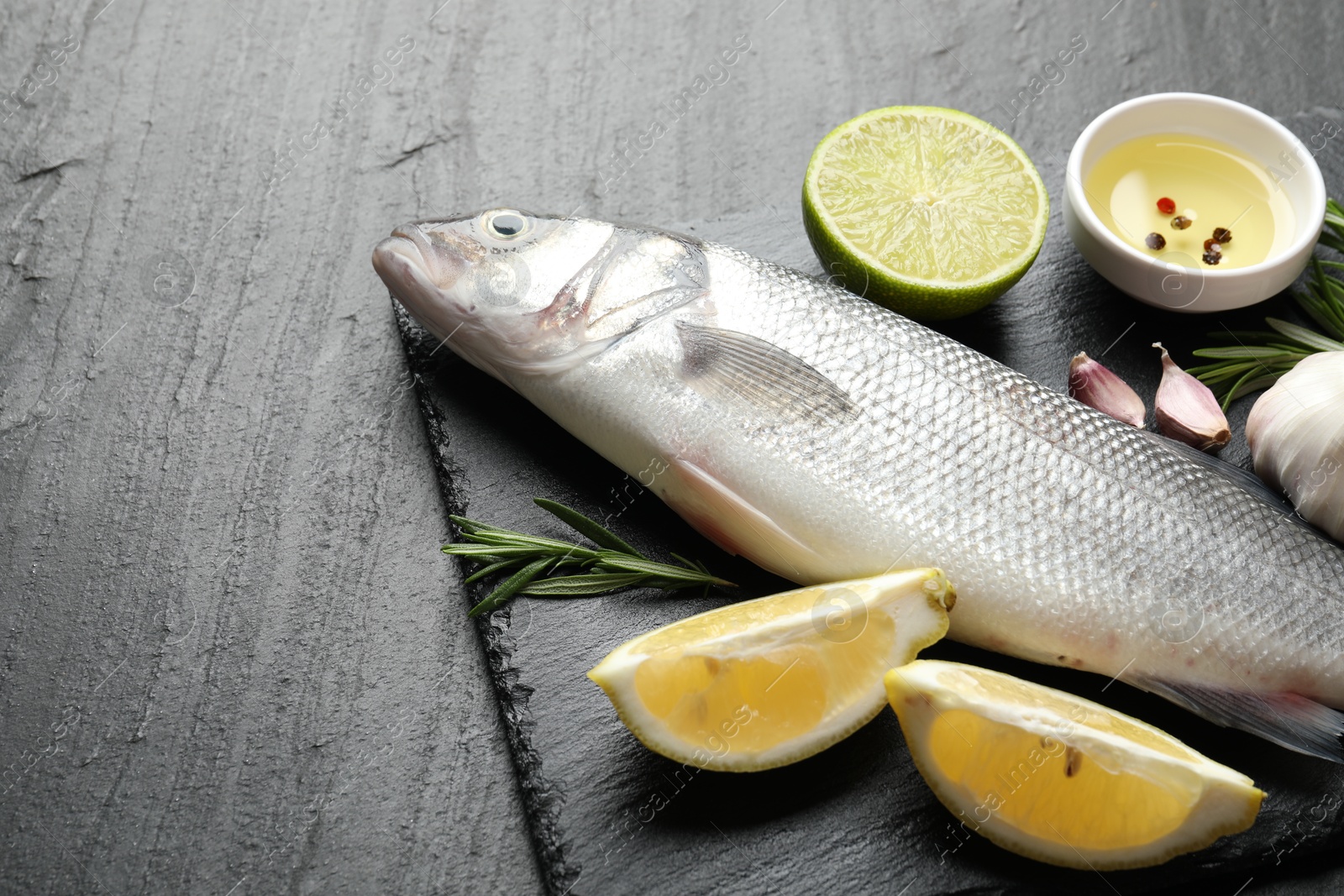 Fresh raw seabass with spices on black table, closeup. Fish and seafood delicacies Photo of Fresh raw seabass with spices on black table, closeup. Fish and seafood delicacies