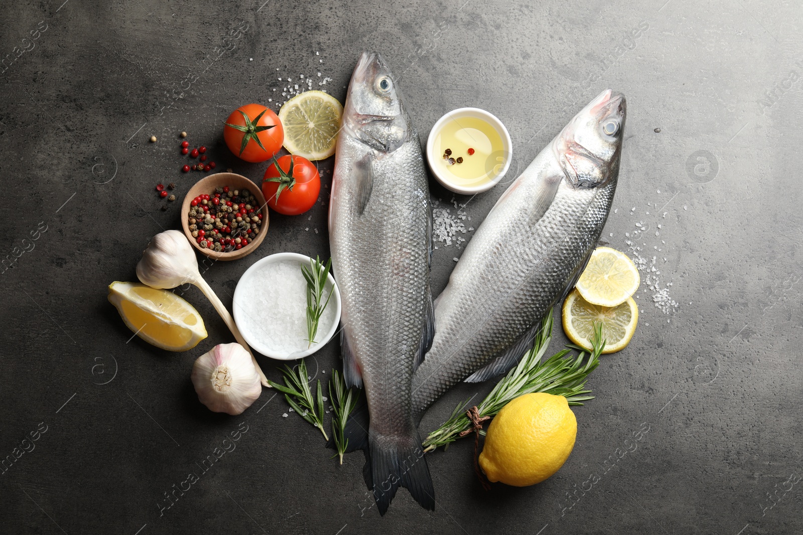 Fresh raw seabass with spices on grey table, flat lay. Fish and seafood delicacies Photo of Fresh raw seabass with spices on grey table, flat lay. Fish and seafood delicacies