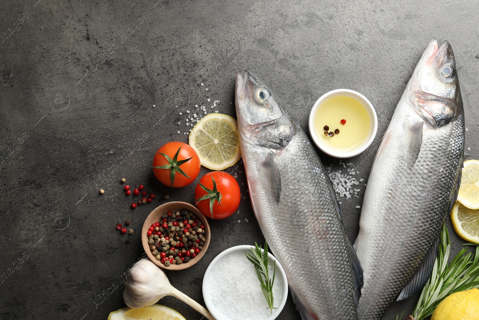 Fresh raw seabass fish with spices on grey table, flat lay and space for text. Seafood delicacies Photo of Fresh raw seabass fish with spices on grey table, flat lay and space for text. Seafood delicacies