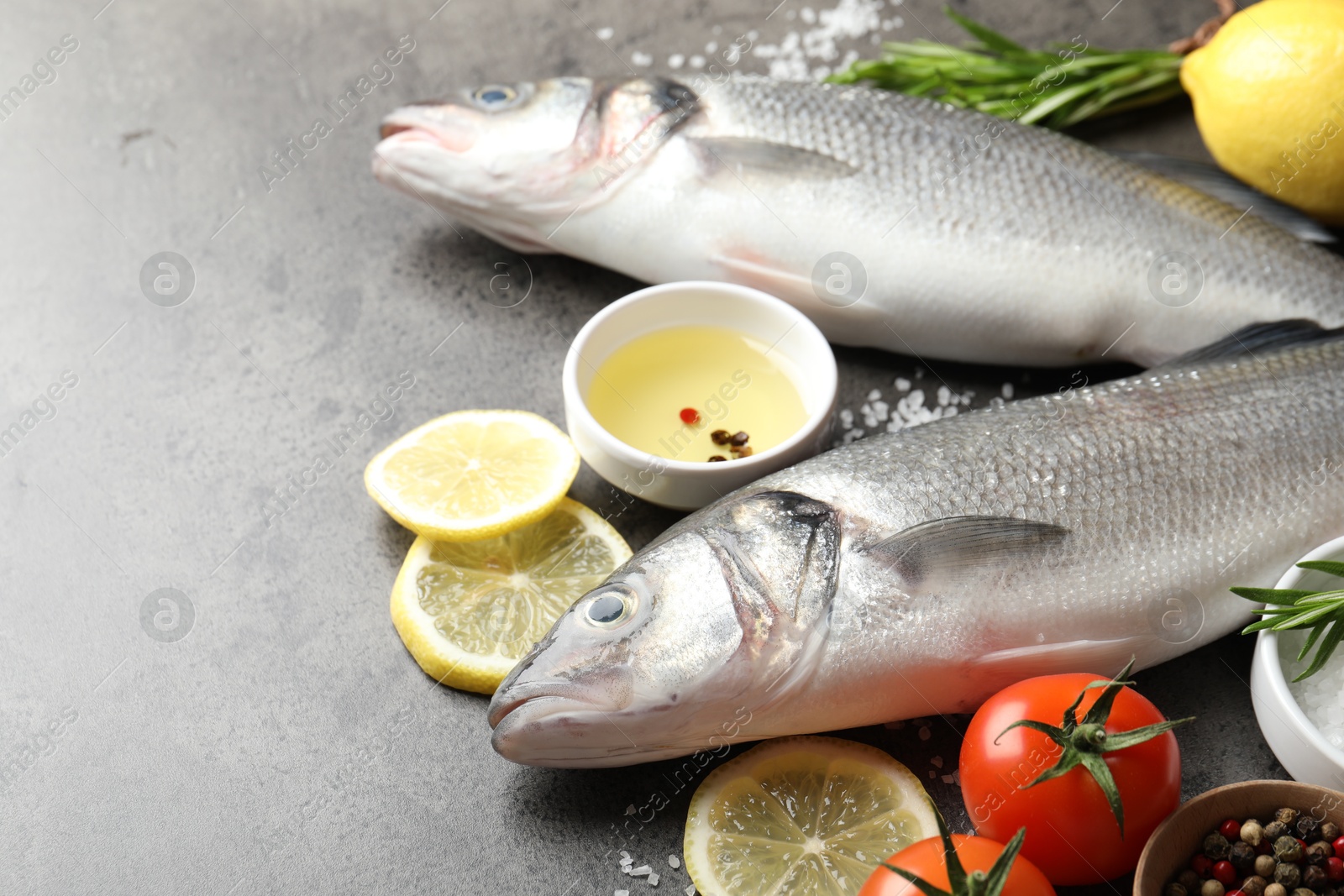 Fresh raw seabass with spices on grey table, closeup. Fish and seafood delicacies Photo of Fresh raw seabass with spices on grey table, closeup. Fish and seafood delicacies