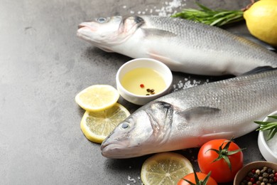 Photo of Fresh raw seabass with spices on grey table, closeup. Fish and seafood delicacies