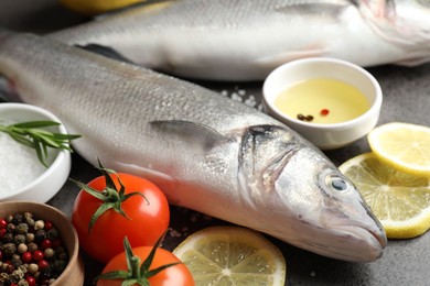 Photo of Fresh raw seabass with spices on grey table, closeup. Fish and seafood delicacies