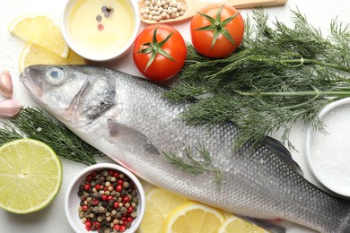 Photo of Fresh raw seabass with spices on white table, flat lay. Fish and seafood delicacies