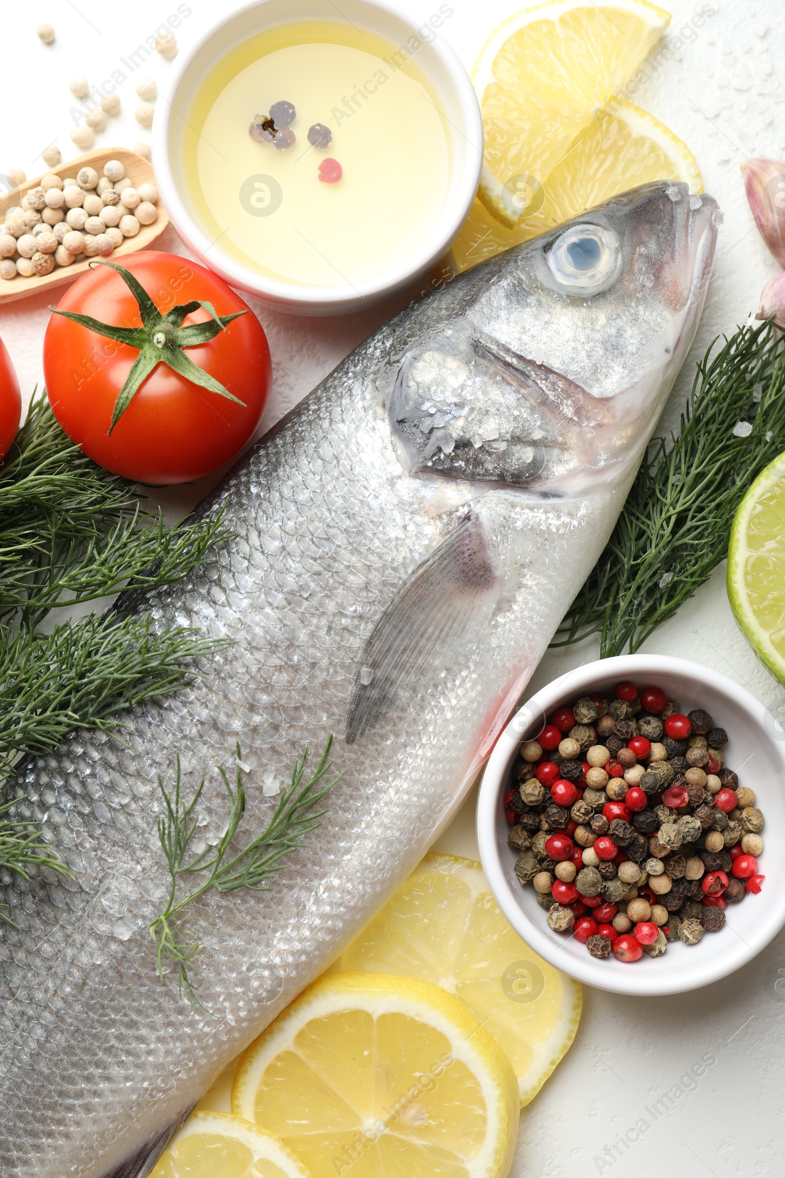 Fresh raw seabass with spices on white table, flat lay. Fish and seafood delicacies Photo of Fresh raw seabass with spices on white table, flat lay. Fish and seafood delicacies