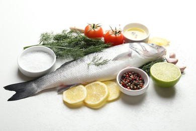 Photo of Fresh raw seabass with spices on white table. Fish and seafood delicacies