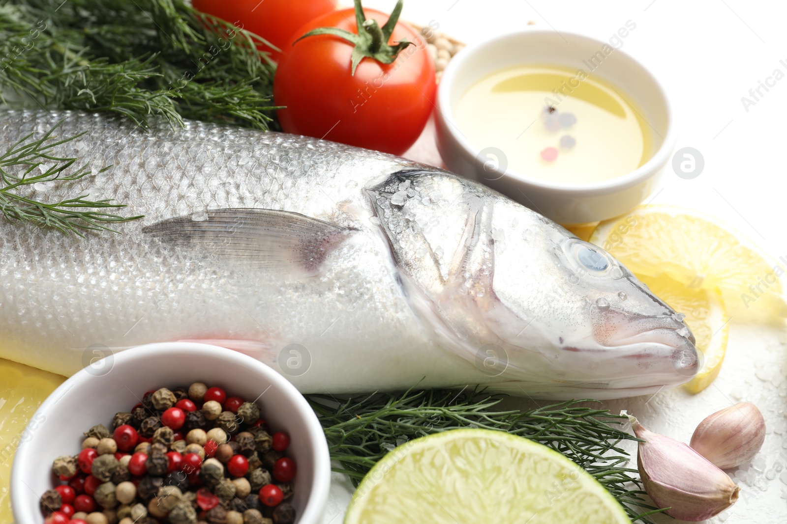 Fresh raw seabass with spices on white table, closeup. Fish and seafood delicacies Photo of Fresh raw seabass with spices on white table, closeup. Fish and seafood delicacies