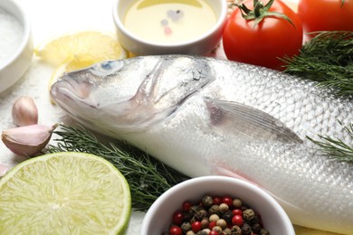 Photo of Fresh raw seabass with spices on white table, closeup. Fish and seafood delicacies