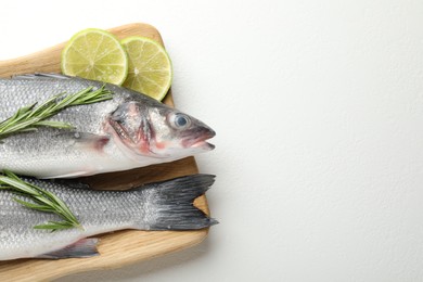 Photo of Fresh raw seabass fish with spices on white table, top view and space for text. Seafood delicacies
