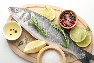 Photo of Fresh raw seabass with spices on white table, top view. Fish and seafood delicacies