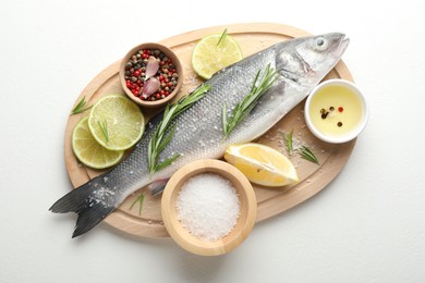 Photo of Fresh raw seabass with spices on white table, top view. Fish and seafood delicacies