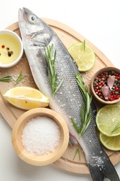 Photo of Fresh raw seabass with spices on white table, top view. Fish and seafood delicacies
