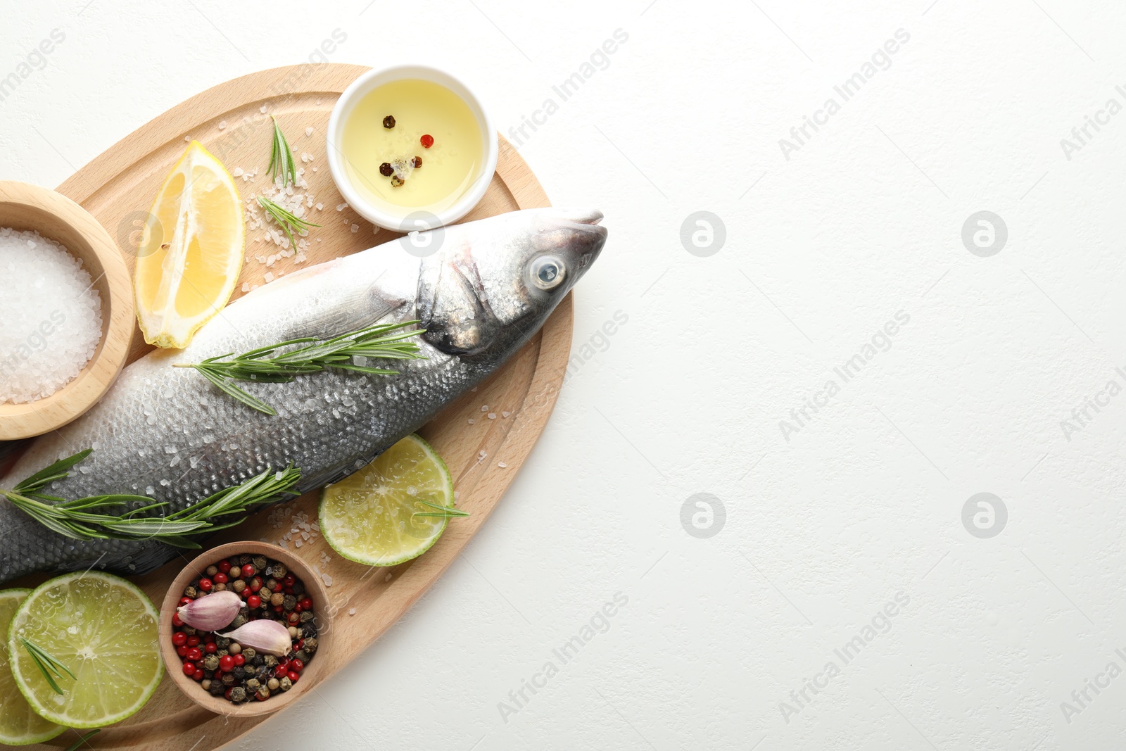 Fresh raw seabass fish with spices on white table, top view and space for text. Seafood delicacies Photo of Fresh raw seabass fish with spices on white table, top view and space for text. Seafood delicacies