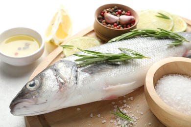 Photo of Fresh raw seabass with spices on white table, closeup. Fish and seafood delicacies