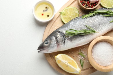 Photo of Fresh raw seabass fish with spices on white table, top view and space for text. Seafood delicacies