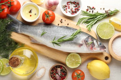 Photo of Fresh raw seabass with spices on white wooden table, flat lay. Fish and seafood delicacies