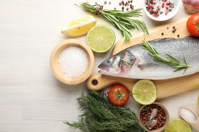 Photo of Fresh raw seabass with spices on white wooden table, flat lay. Fish and seafood delicacies