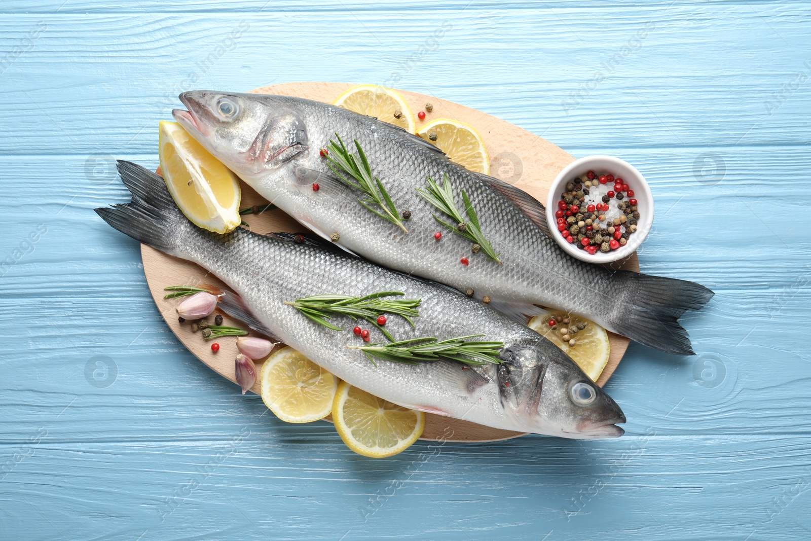 Fresh raw seabass with spices on blue wooden table, top view. Fish and seafood delicacies Photo of Fresh raw seabass with spices on blue wooden table, top view. Fish and seafood delicacies