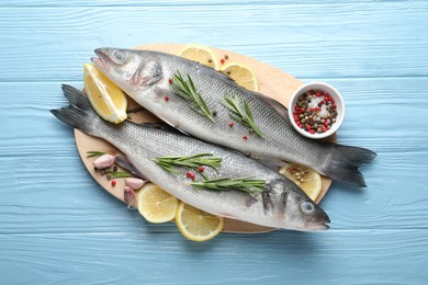 Photo of Fresh raw seabass with spices on blue wooden table, top view. Fish and seafood delicacies