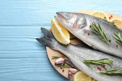 Photo of Fresh raw seabass fish with spices on blue wooden table, top view and space for text. Seafood delicacies