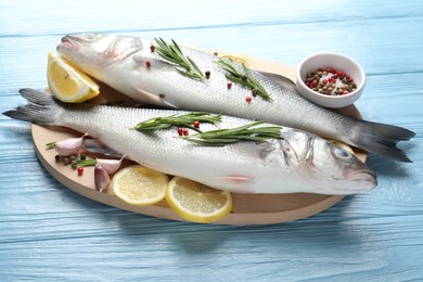 Photo of Fresh raw seabass with spices on blue wooden table, closeup. Fish and seafood delicacies