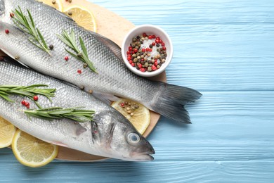 Photo of Fresh raw seabass fish with spices on blue wooden table, top view and space for text. Seafood delicacies