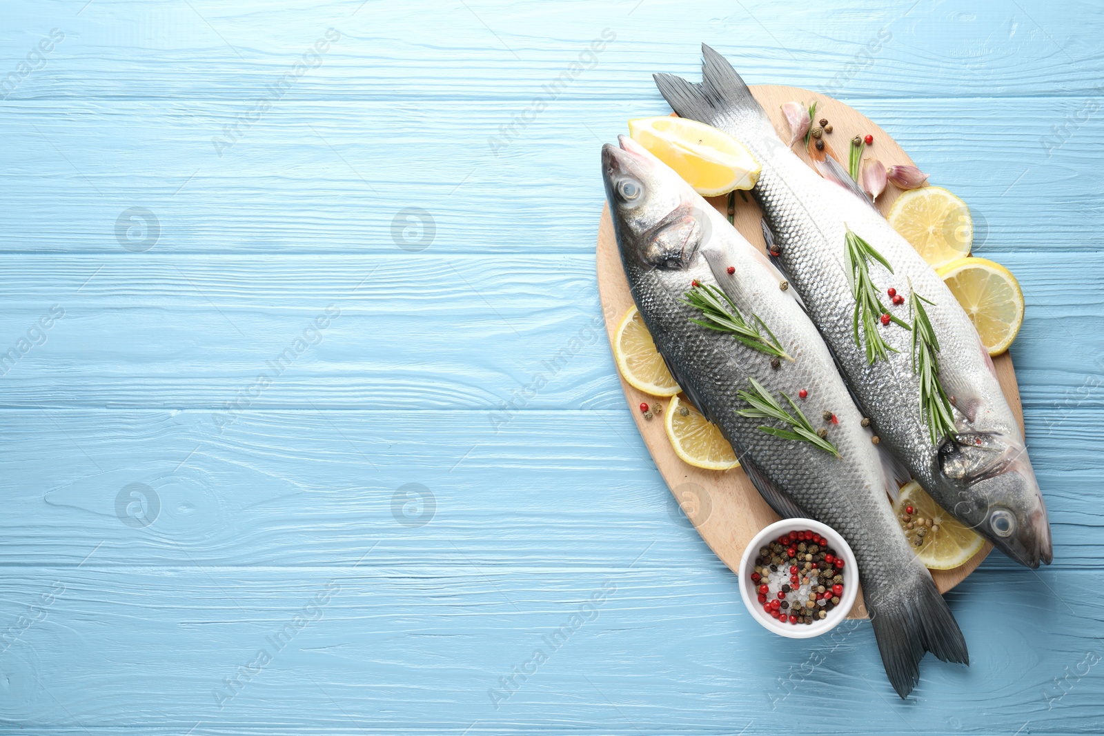 Fresh raw seabass fish with spices on blue wooden table, top view and space for text. Seafood delicacies Photo of Fresh raw seabass fish with spices on blue wooden table, top view and space for text. Seafood delicacies