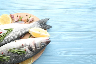 Photo of Fresh raw seabass fish with spices on blue wooden table, top view and space for text. Seafood delicacies