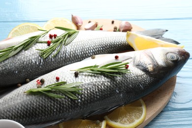 Photo of Fresh raw seabass with spices on blue wooden table, closeup. Fish and seafood delicacies