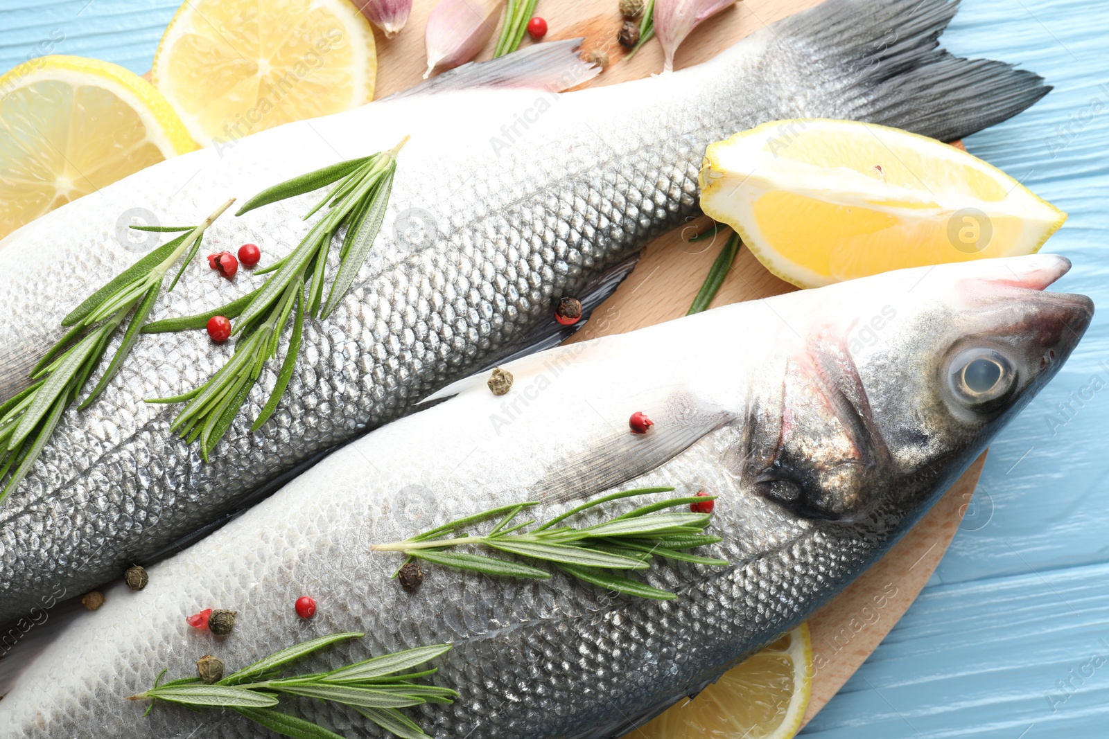 Fresh raw seabass with spices on blue wooden table, closeup. Fish and seafood delicacies Photo of Fresh raw seabass with spices on blue wooden table, closeup. Fish and seafood delicacies