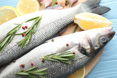 Photo of Fresh raw seabass with spices on blue wooden table, closeup. Fish and seafood delicacies