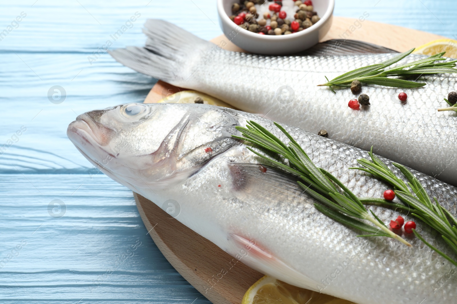 Fresh raw seabass with spices on blue wooden table, closeup. Fish and seafood delicacies Photo of Fresh raw seabass with spices on blue wooden table, closeup. Fish and seafood delicacies